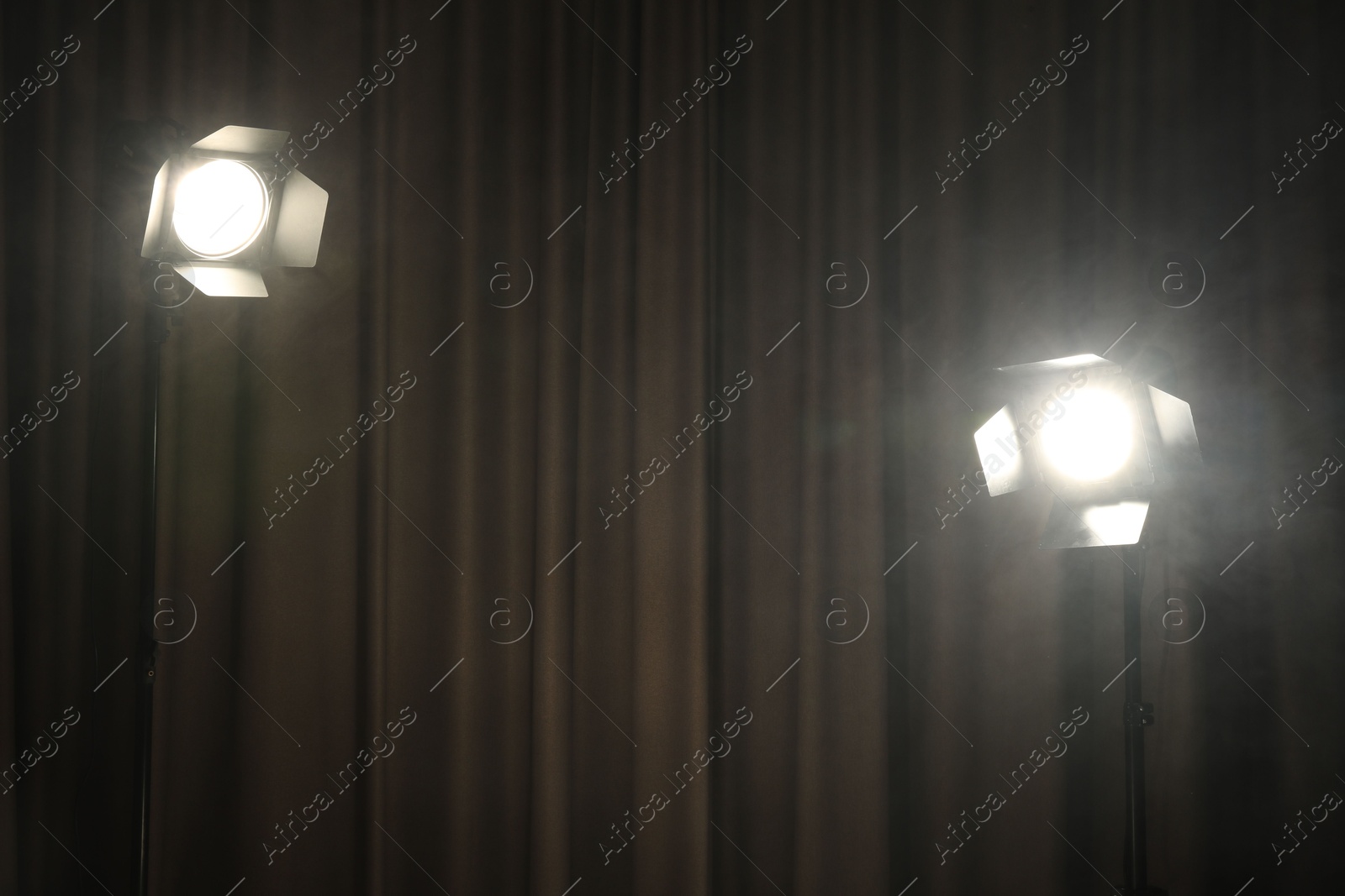 Photo of Spotlights and smoke against curtain. Professional lighting equipment