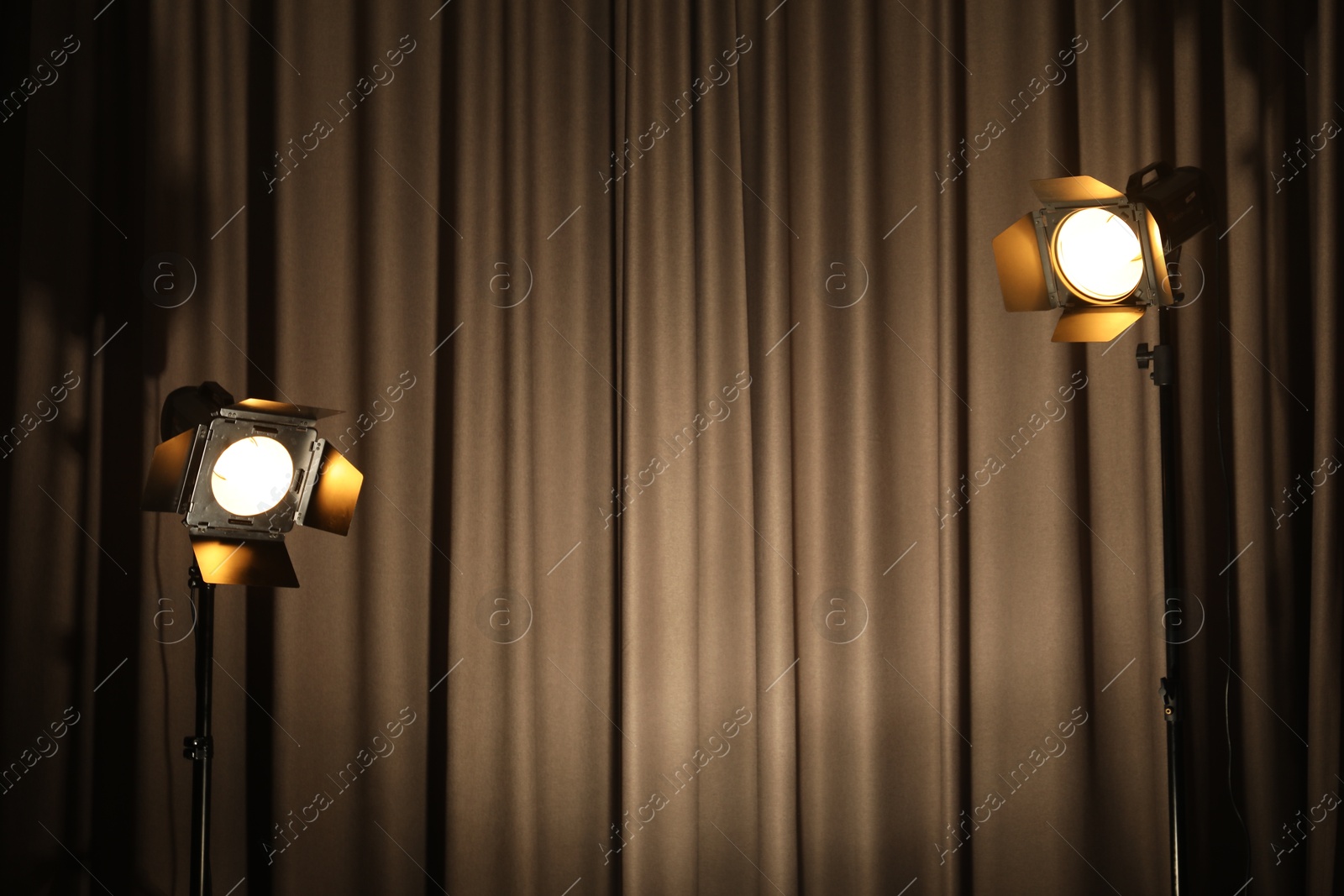 Photo of Two spotlights against curtain. Professional lighting equipment