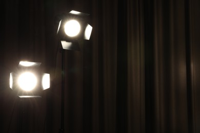 Photo of Professional spotlights against curtain. Space for text