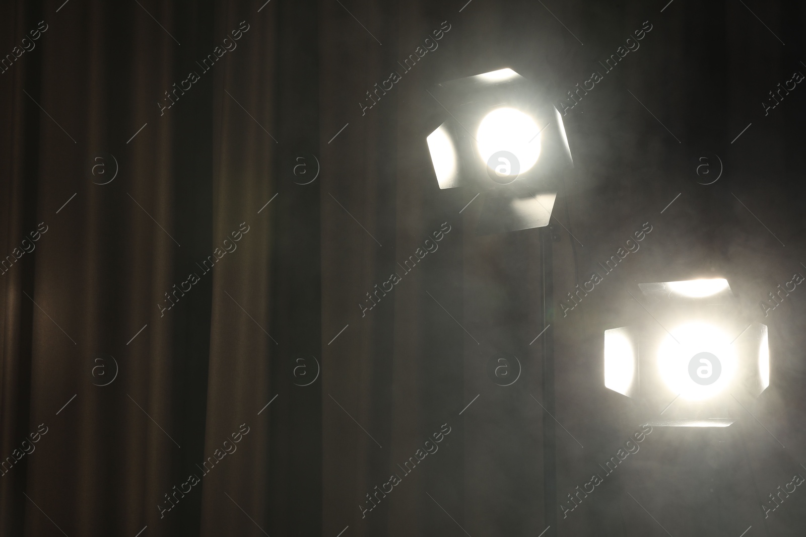 Photo of Professional spotlights and smoke against curtain. Space for text