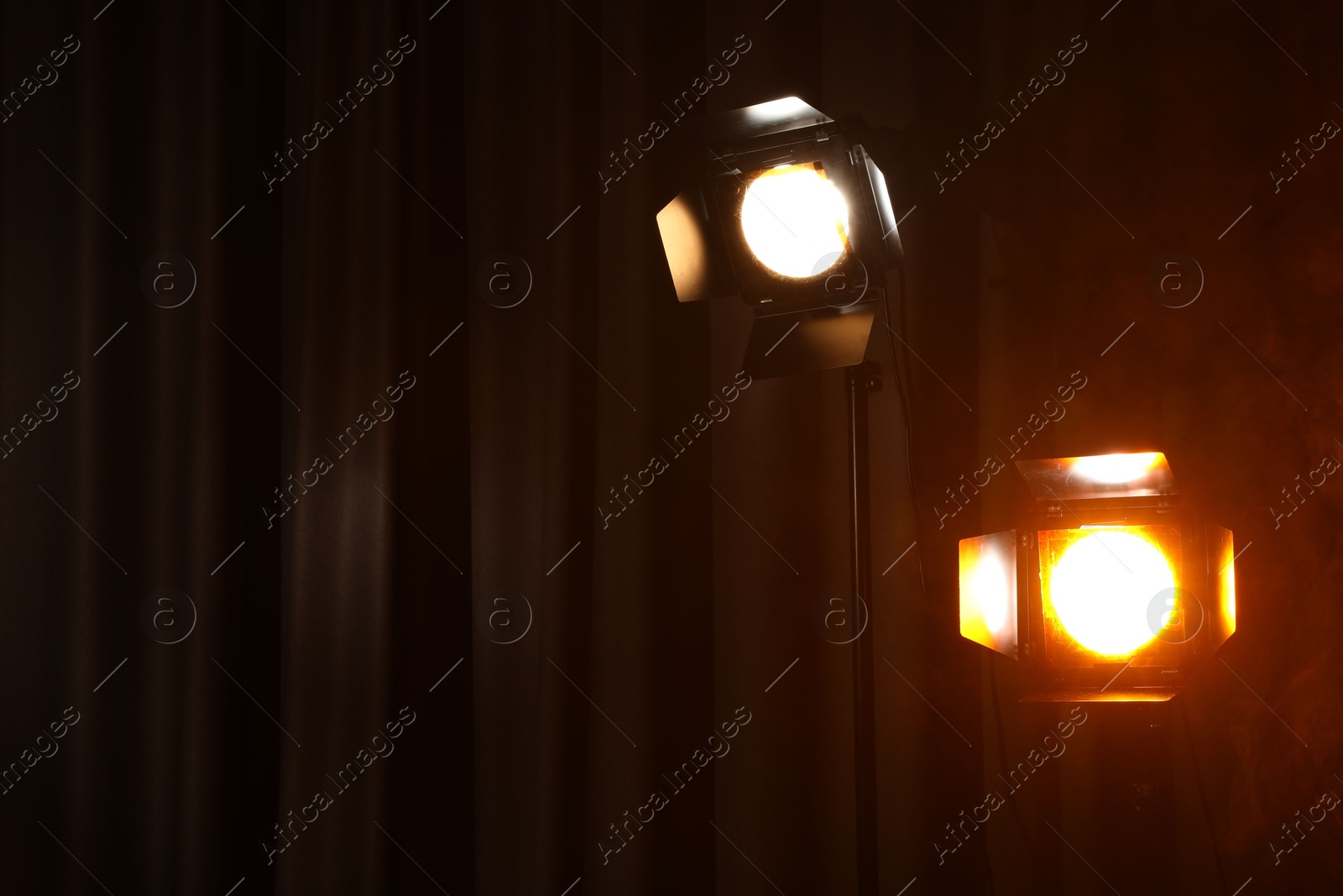 Photo of Professional spotlights against curtain. Space for text