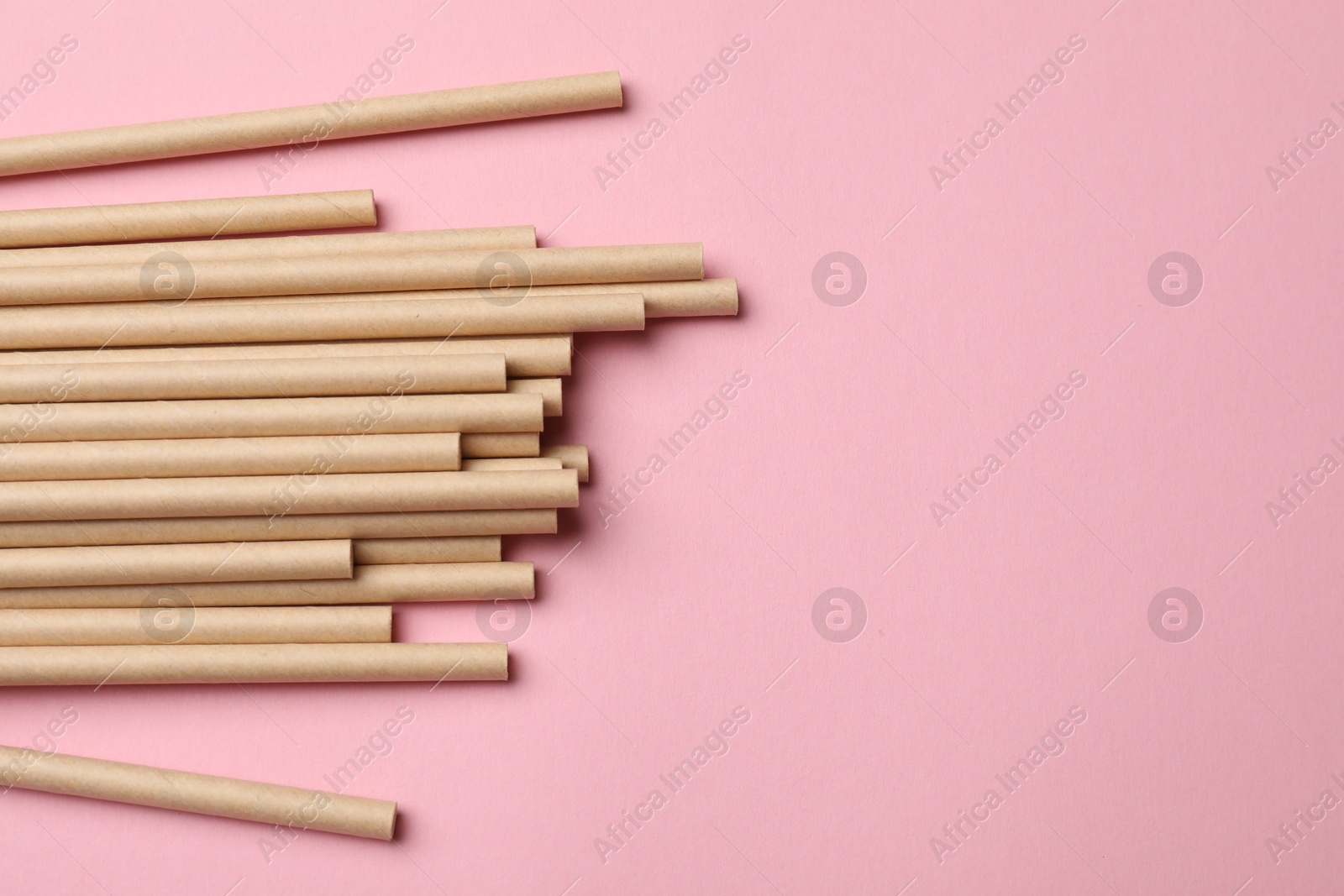 Photo of Bamboo drinking straws on pink background, top view. Space for text