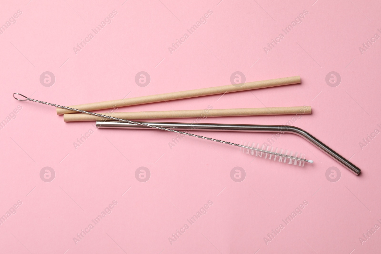 Photo of Reusable drinking straws and cleaning brush on pink background, top view