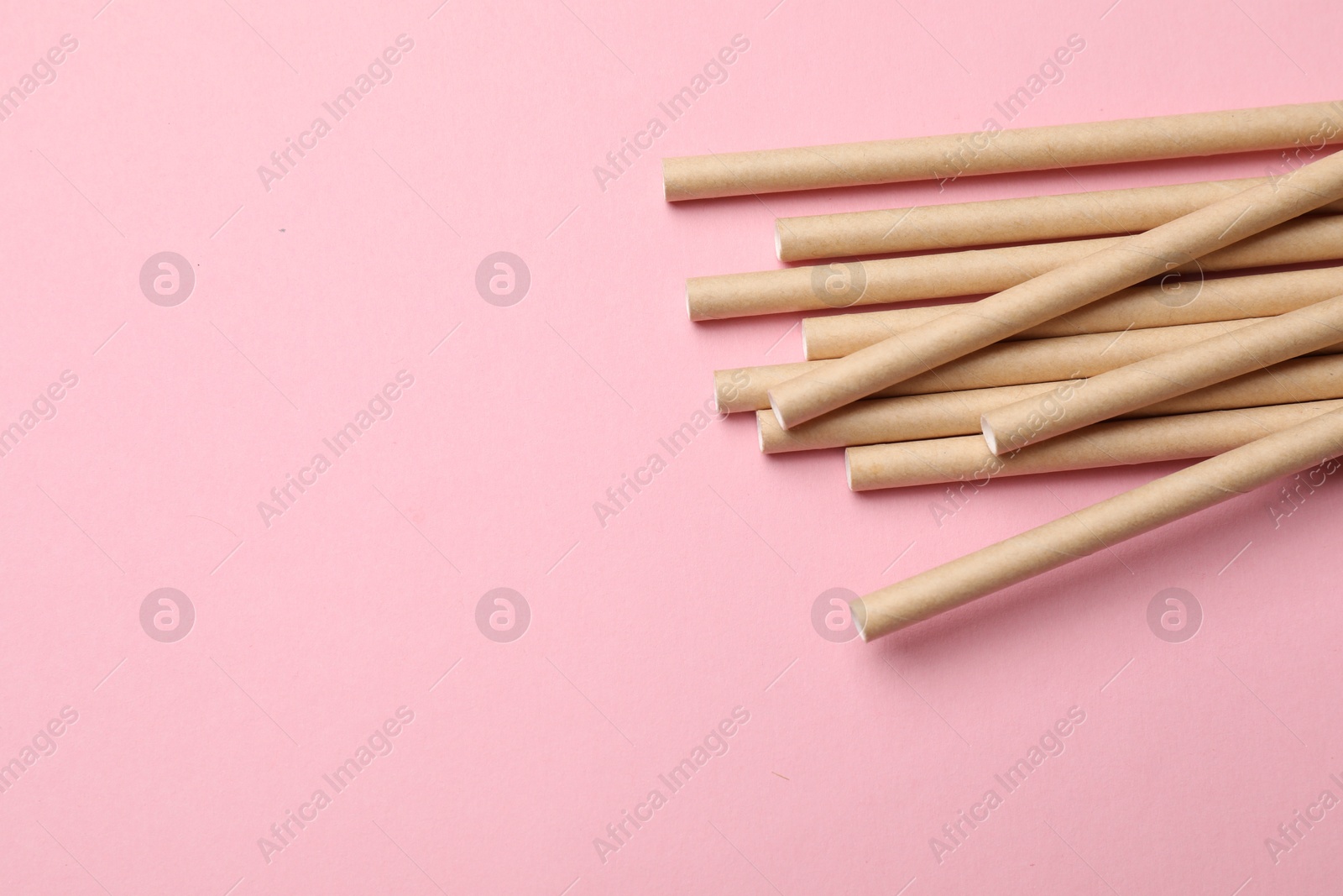 Photo of Bamboo drinking straws on pink background, top view. Space for text