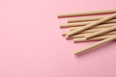 Photo of Bamboo drinking straws on pink background, top view. Space for text