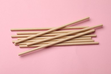 Photo of Bamboo drinking straws on pink background, top view