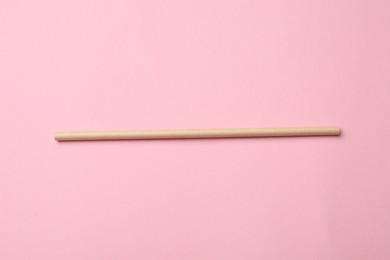 Photo of One bamboo drinking straw on pink background, top view