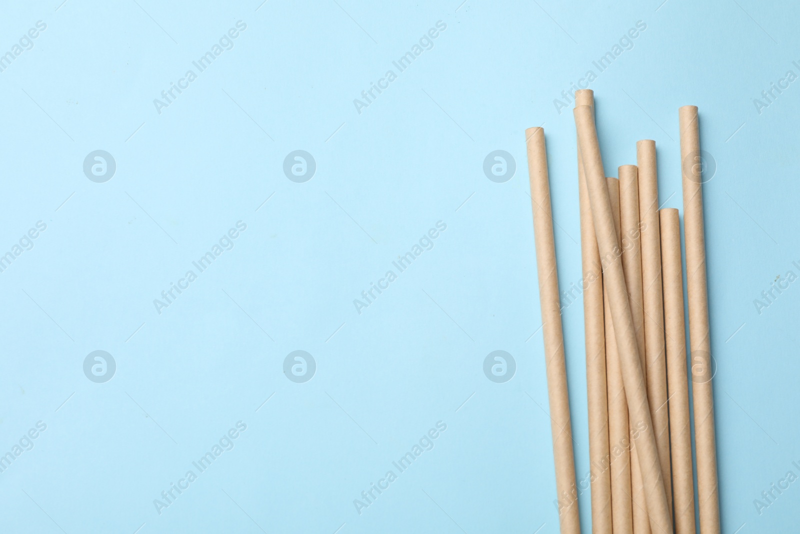 Photo of Bamboo drinking straws on light blue background, top view. Space for text