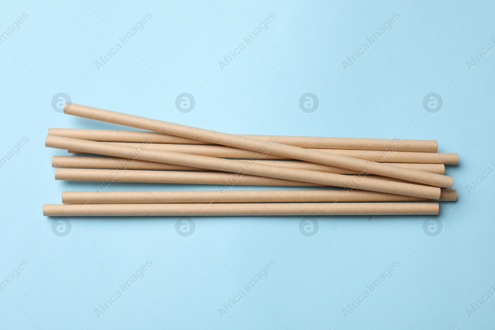 Photo of Bamboo drinking straws on light blue background, top view