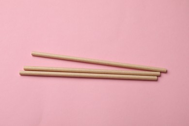 Photo of Bamboo drinking straws on pink background, top view