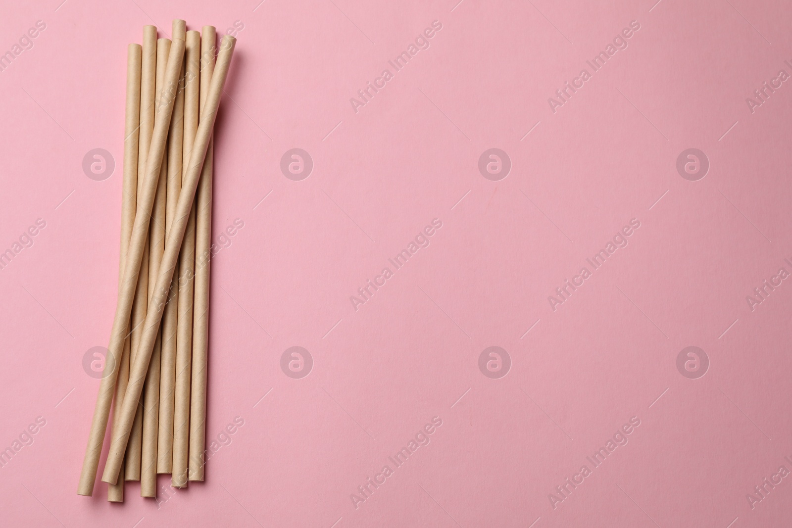 Photo of Bamboo drinking straws on pink background, top view. Space for text