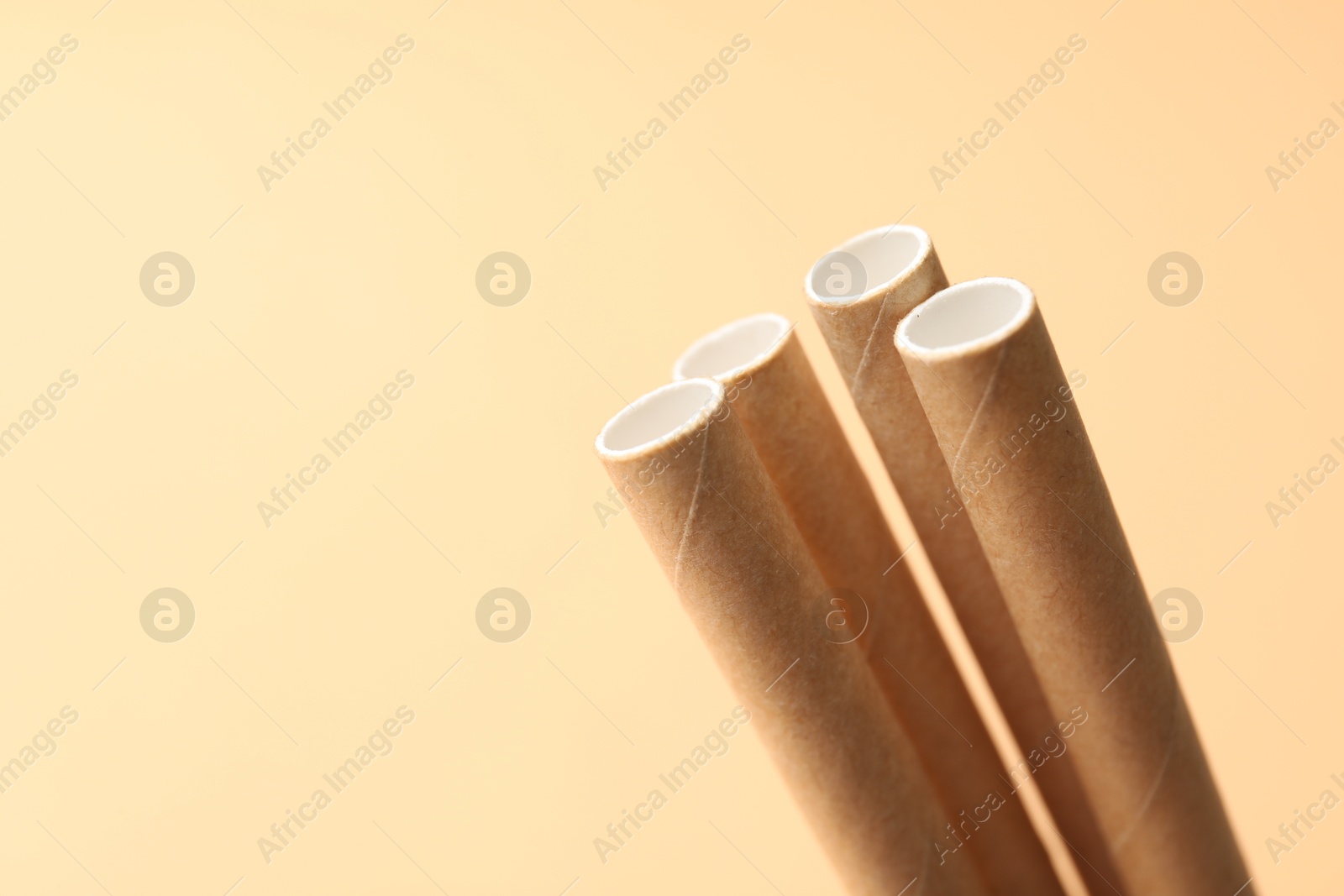 Photo of Bamboo drinking straws on beige background, closeup. Space for text