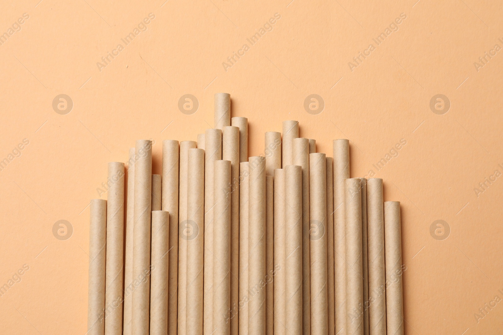 Photo of Bamboo drinking straws on beige background, top view