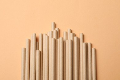 Photo of Bamboo drinking straws on beige background, top view