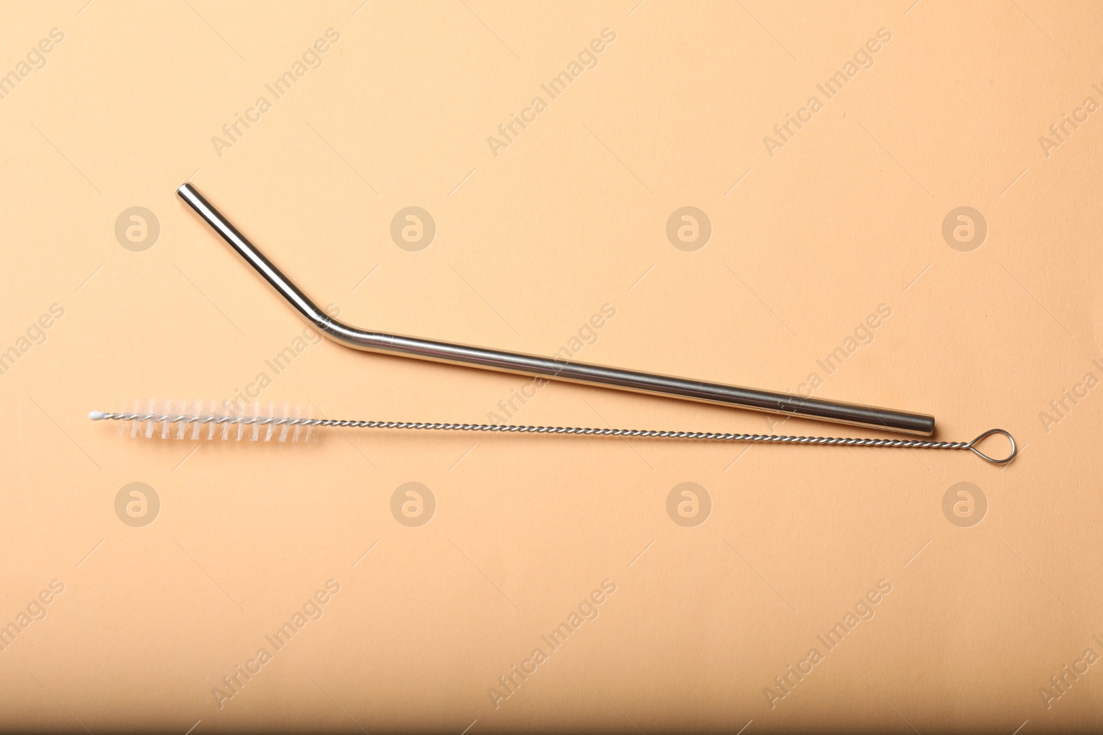 Photo of Metal drinking straw and cleaning brush on beige background, top view