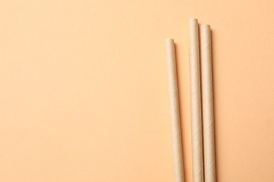 Photo of Bamboo drinking straws on beige background, top view. Space for text