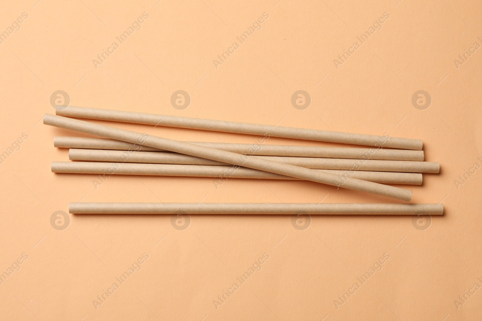 Photo of Bamboo drinking straws on beige background, top view