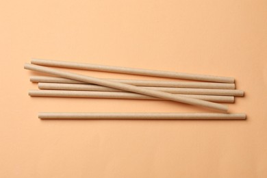 Photo of Bamboo drinking straws on beige background, top view