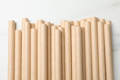 Photo of Many bamboo drinking straws on white table, top view