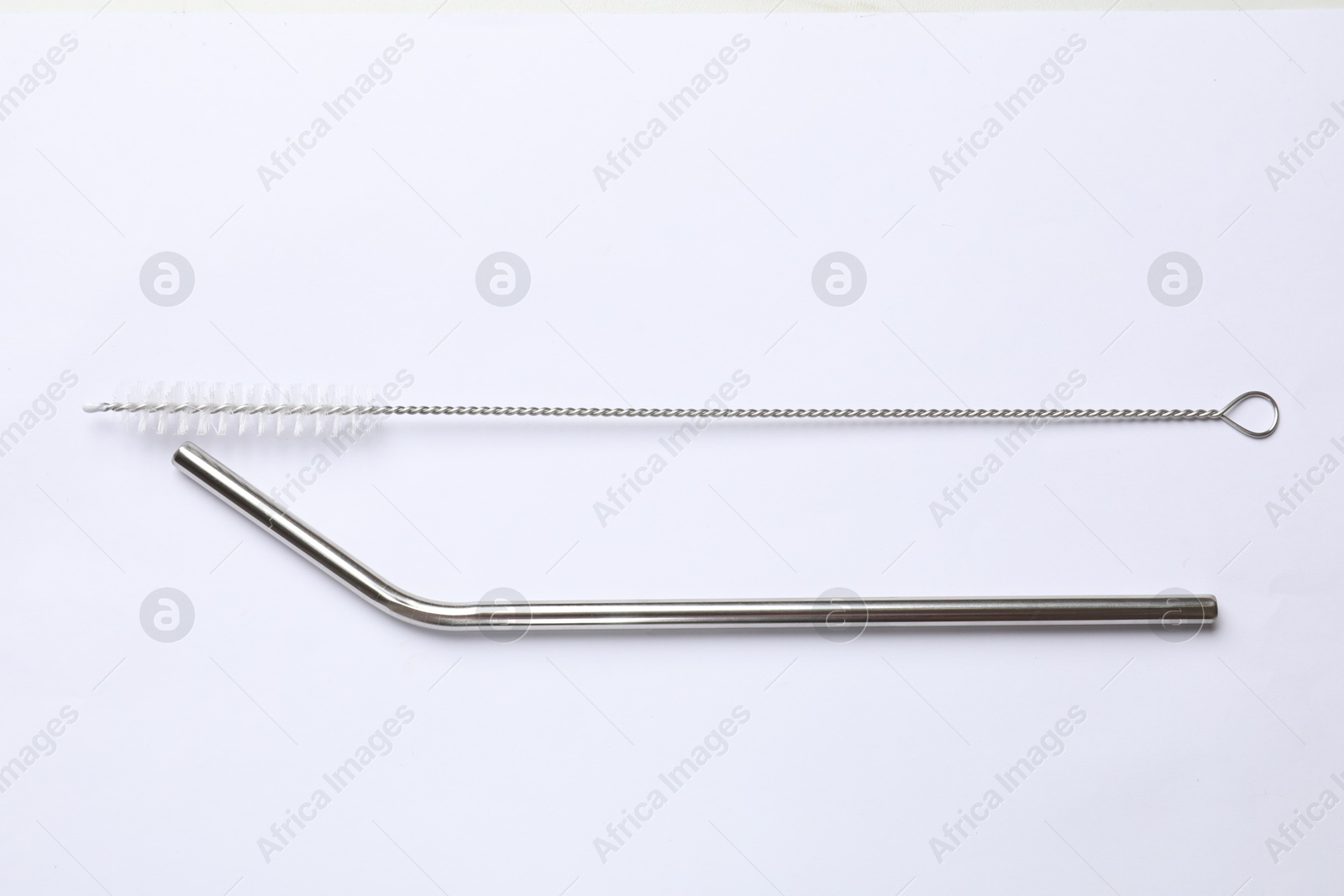 Photo of Metal drinking straw and cleaning brush isolated on white, top view