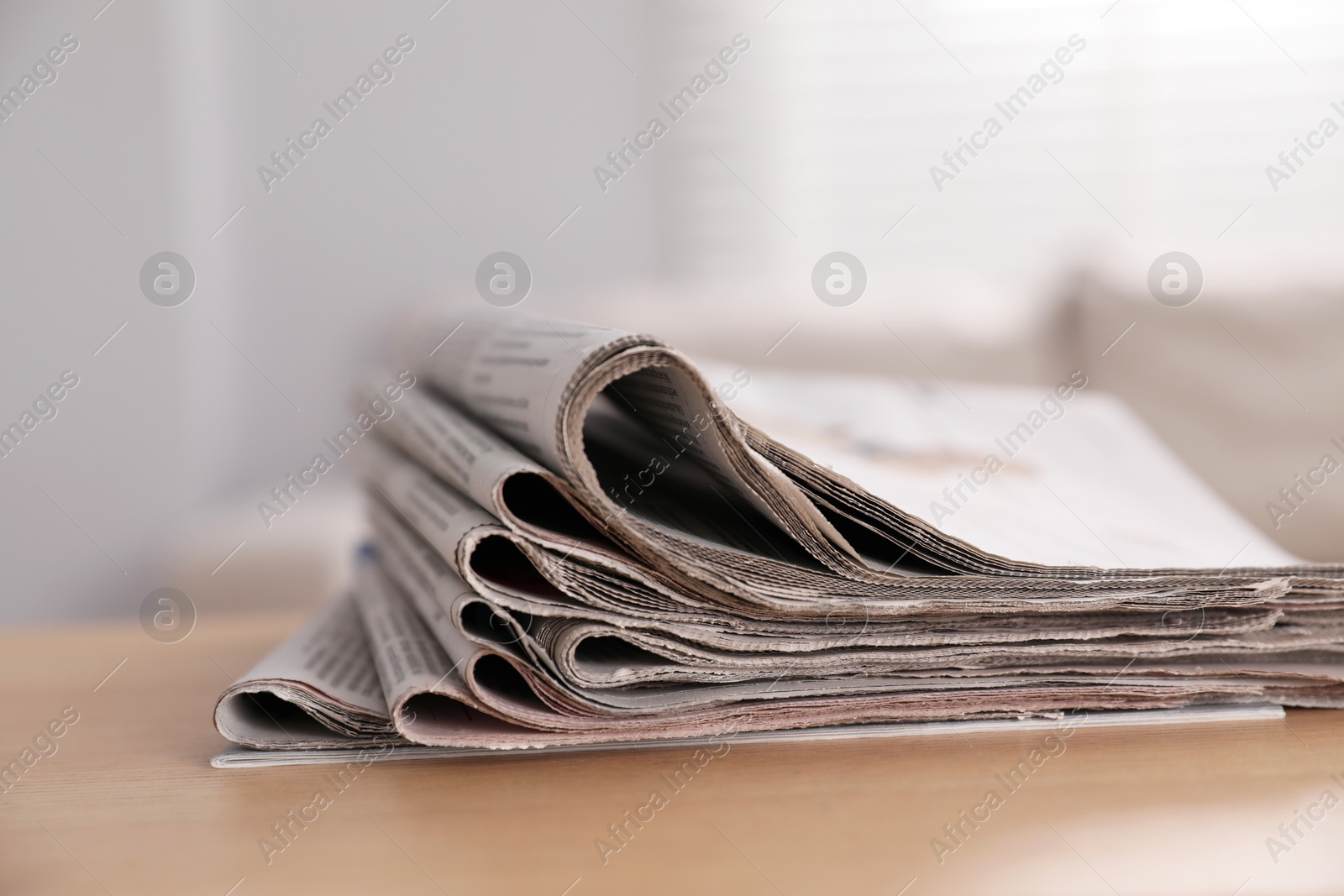 Photo of Stack of newspapers in different languages on table indoors, closeup