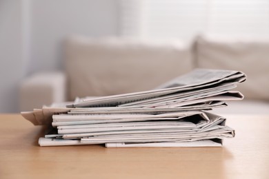 Photo of Stack of newspapers in different languages on table indoors