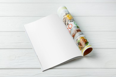 Open magazine with blank page on white wooden table. Mockup for design