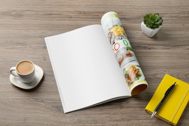 Photo of Open magazine with blank page, coffee, plant and stationery on wooden table. Mockup for design