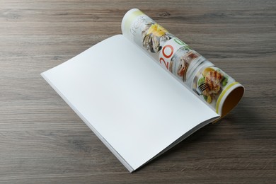 Photo of Open magazine with blank page on wooden table. Mockup for design