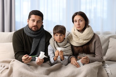 Photo of Cold symptom. Family suffering from fever on sofa at home