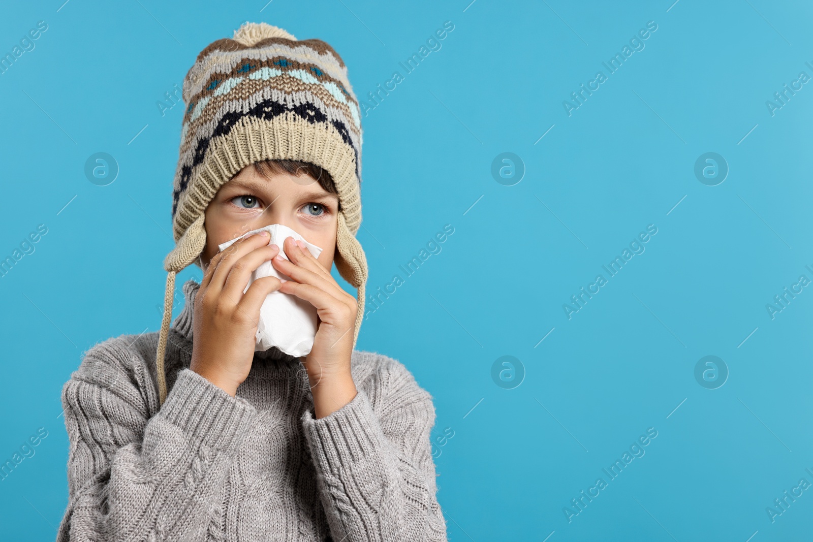 Photo of Cold symptom. Little boy with runny nose on light blue background, space for text