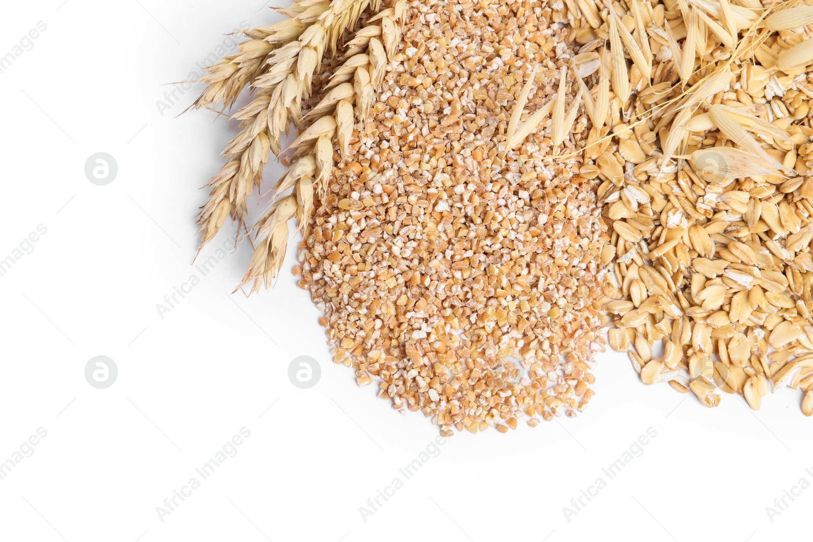 Photo of Raw wheat groats, oat flakes and spikelets isolated on white, top view