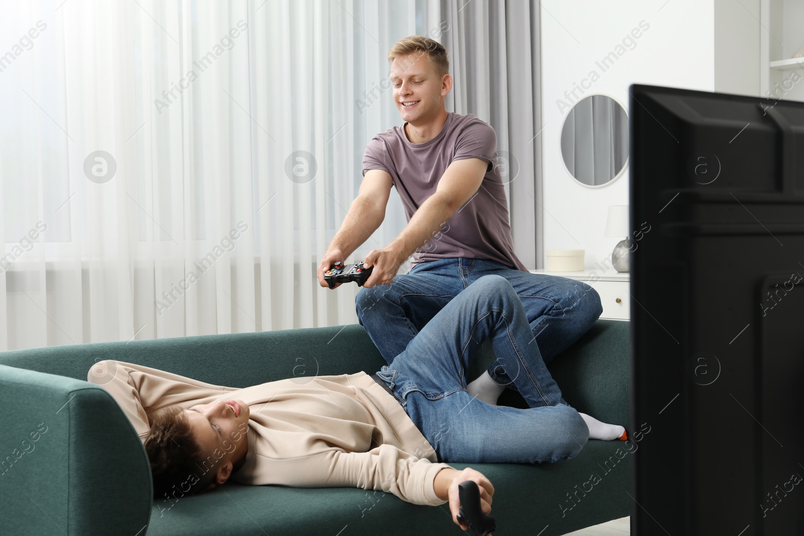 Photo of Young brothers playing video game on sofa at home