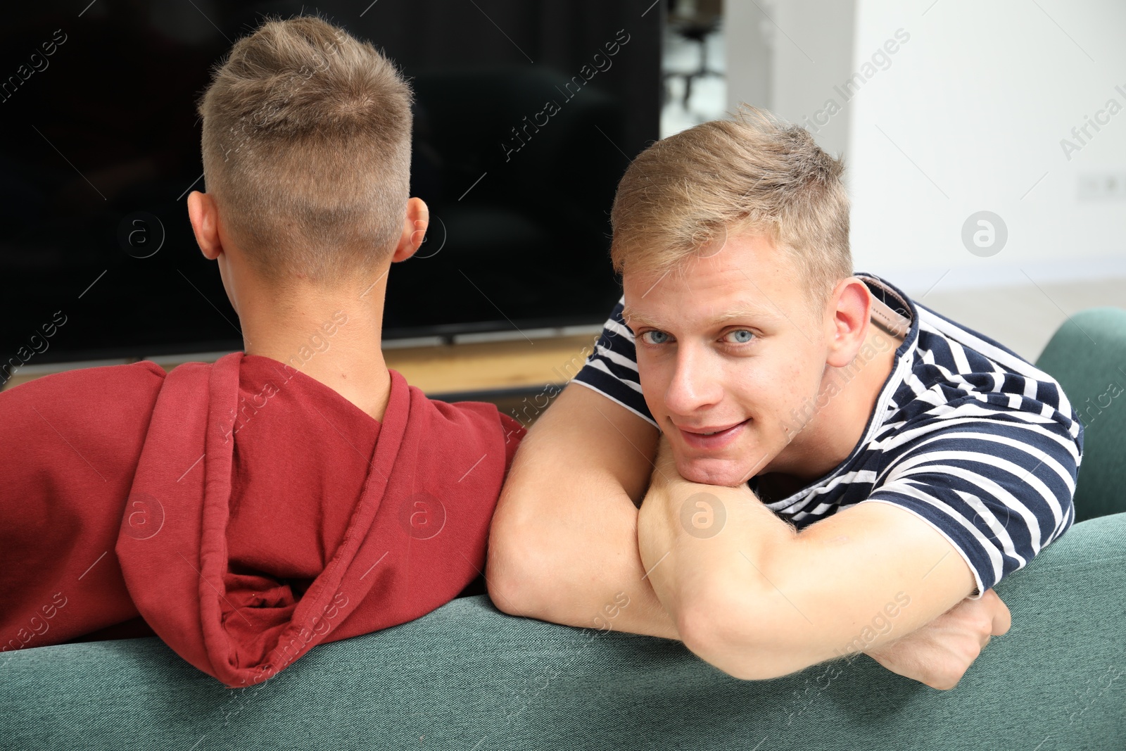 Photo of Young brothers spending time together on sofa at home