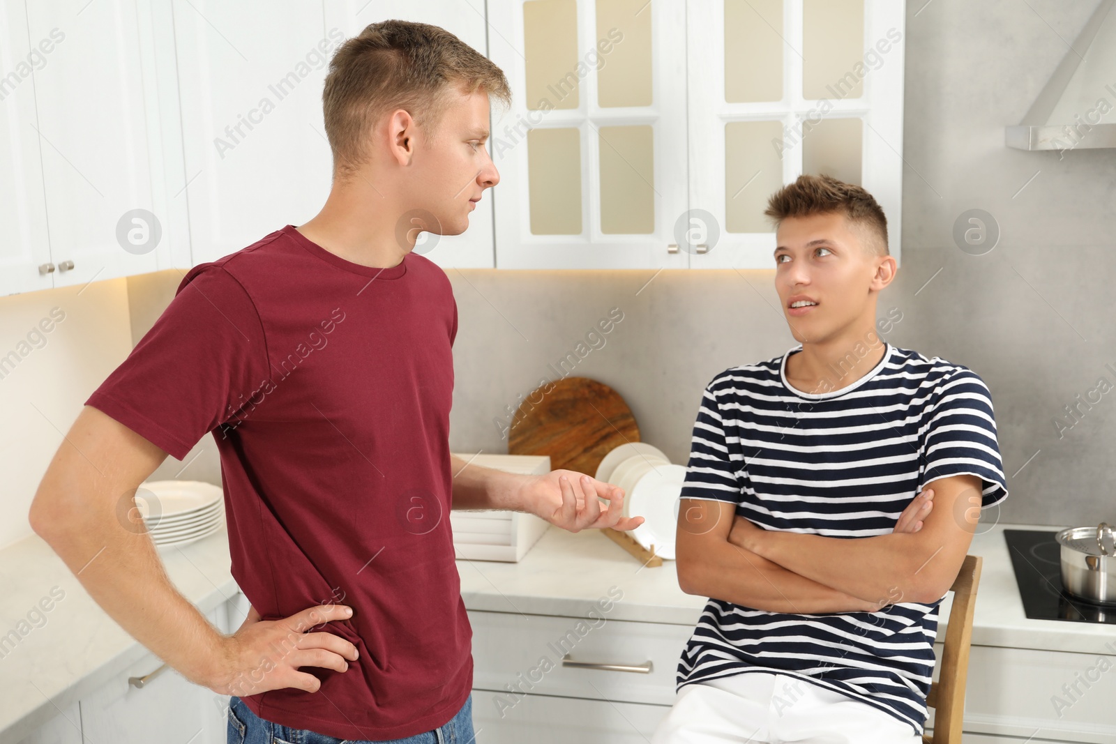 Photo of Young brothers talking in kitchen at home