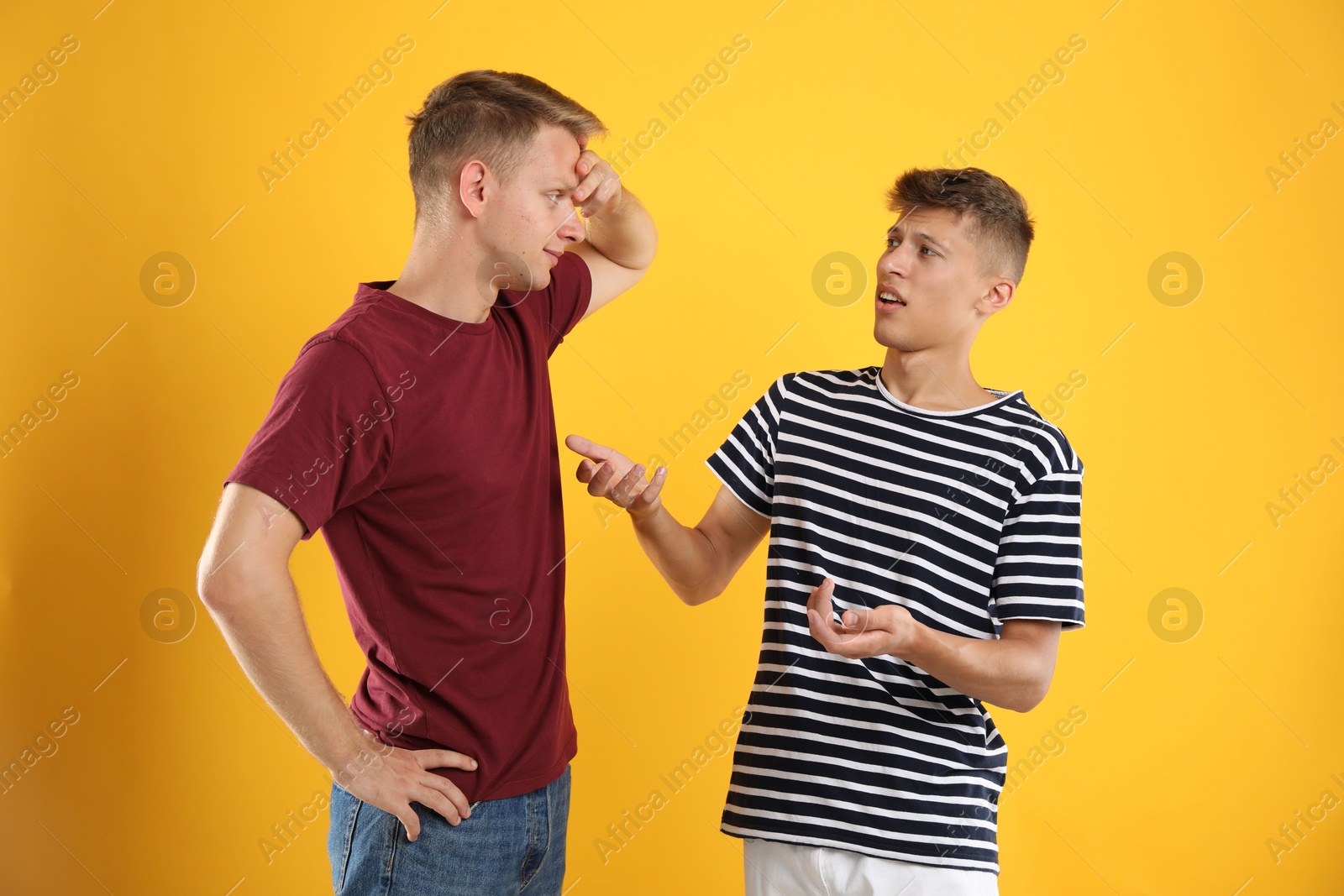 Photo of Two young brothers talking on orange background