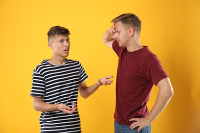 Photo of Two young brothers talking on orange background