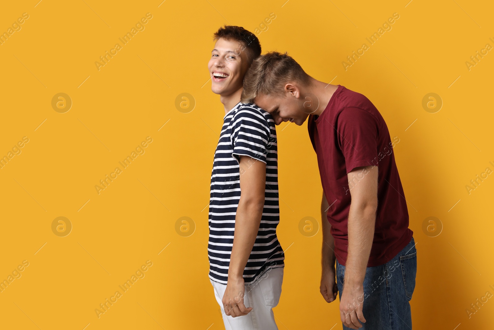 Photo of Portrait of happy brothers on orange background. Space for text