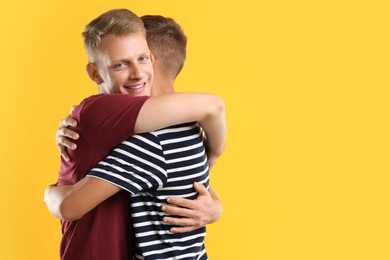 Happy brothers hugging on orange background. Space for text