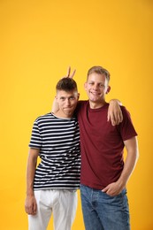 Portrait of funny brothers on orange background