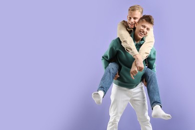 Photo of Happy brothers having fun on violet background. Space for text