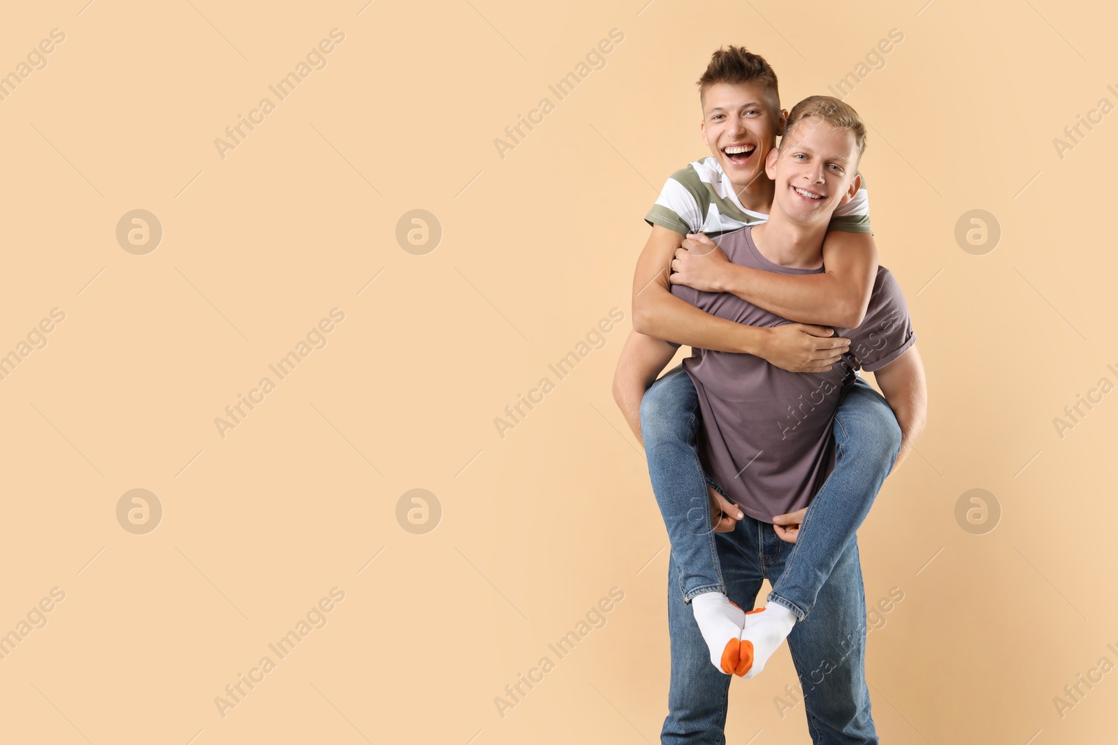 Photo of Happy brothers on beige background. Space for text