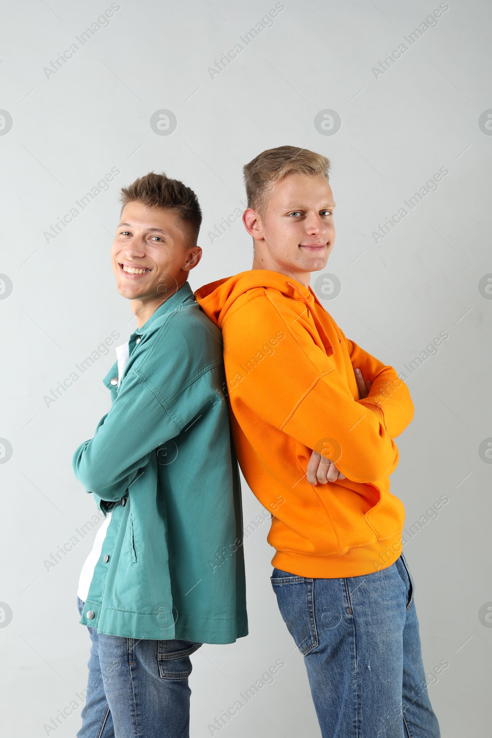 Photo of Portrait of two happy brothers posing with crossed arms on light background