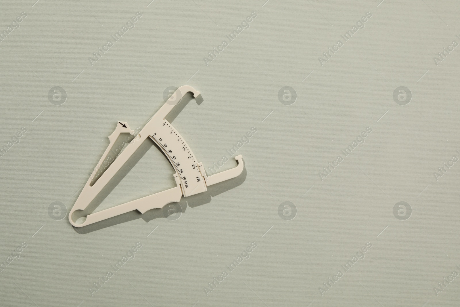 Photo of Plastic body fat caliper on grey background, top view. Space for text