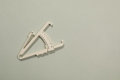 Photo of Plastic body fat caliper on grey background, top view. Space for text