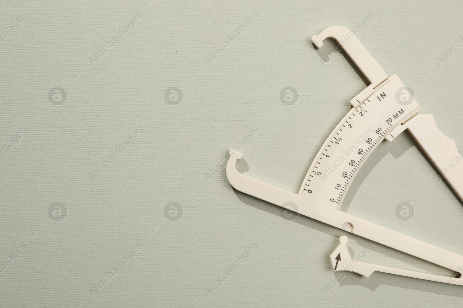 Photo of Plastic body fat caliper on grey background, top view. Space for text