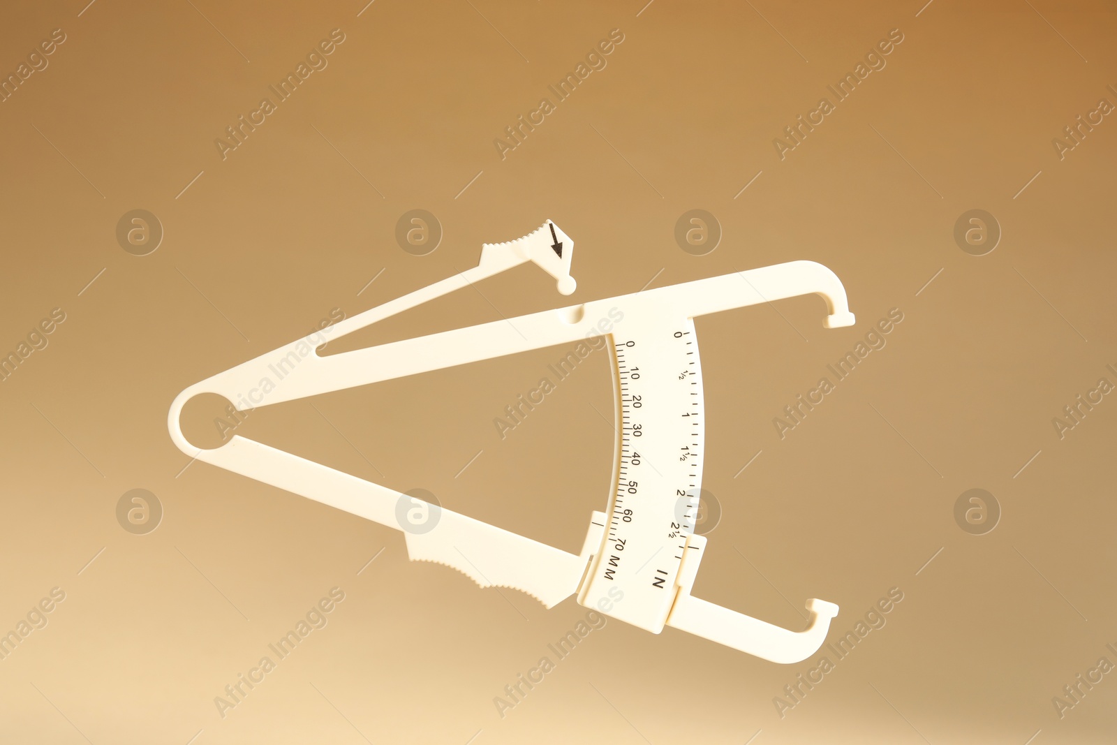 Photo of Plastic body fat caliper on beige background