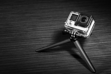 Modern action camera and tripod on grey wooden surface