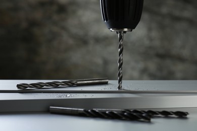 Photo of Drilling hole in plank on table against gray background, closeup