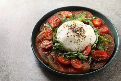 Photo of Delicious fresh burrata salad in bowl on gray textured table, closeup